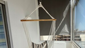 A room with a hanging chair, a window, and a view of buildings. - Azul,: A cozy apartment just a few steps from Praia da Rocha (Portimão)