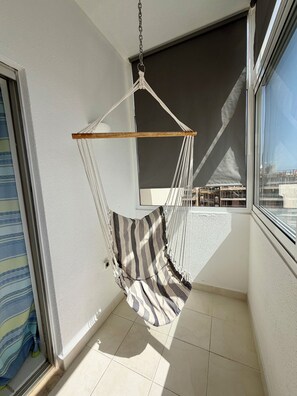 A room with a hanging chair, a window, and a view of buildings. - Azul,: A cozy apartment just a few steps from Praia da Rocha (Portimão)