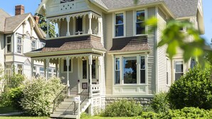 Ein zweistöckiges Haus mit Veranda, Schornstein und einem gepflegten Garten.