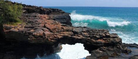 A rocky coastline with a natural arch formation and waves crashing against the rocks.