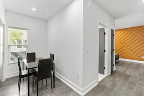 A modern interior with a dining area, a wooden accent wall, and a hallway leading to another room.