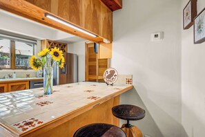 A kitchen with a wooden countertop, a vase with sunflowers, and a wall-mounted oven. - Long-Term Rental, Walk to the Plaza, Near Sprouts (Santa Fe)