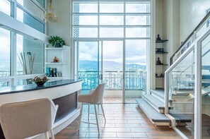 A modern kitchen with a large window, a bar area, and a view of the city. - The Cebu Skyline Penthouse Romantic Getaway with Pool, King size Bed, 2 BR (Cebu City)