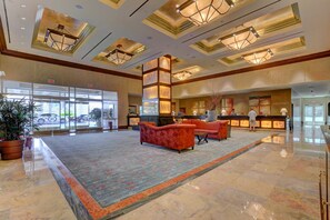 A spacious lobby with a reception desk, plush seating, and a large window offering a view of the parking area. - Upscale Strip View Suite | Jacuzzi & Kitchenette (Las Vegas)