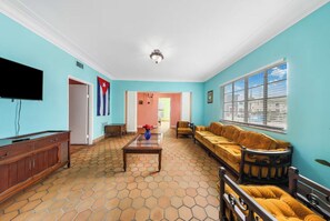 Ein Wohnzimmer mit Fliesenboden, Fernseher, Sofa und Couchtisch.