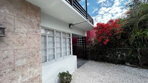 Un edificio moderno con facciata bianca, un'ampia porta garage e un vialetto sterrato.