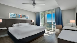 A hotel room with a large bed, a ceiling fan, a view of the ocean, a desk, and a chair. - Myrtle Beach Oceanfront Stay with Pool & Spacious 1BR Plus Suite (Myrtle Beach)