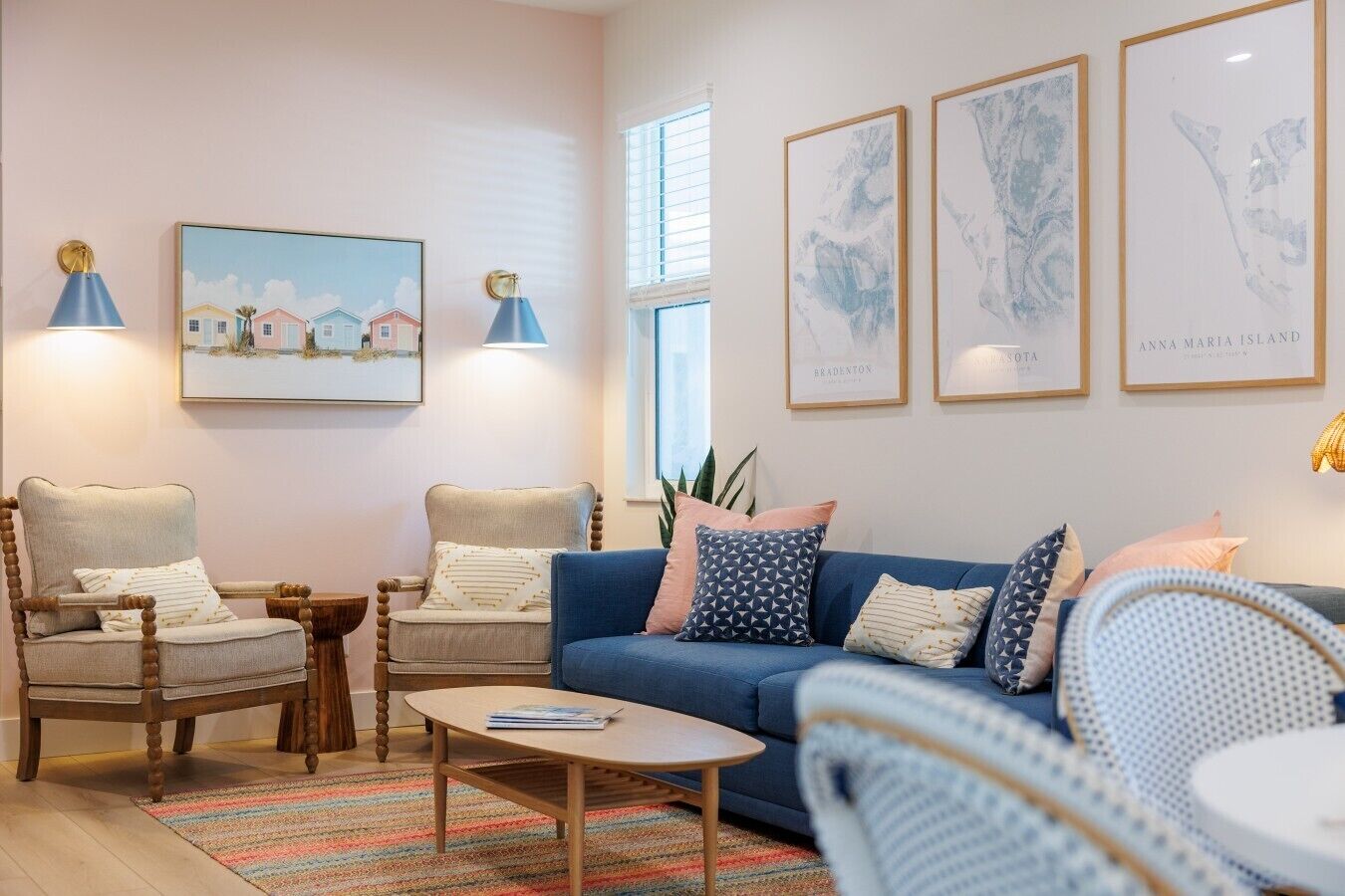 A living room with a blue sofa, two armchairs, a coffee table, and framed artwork on the walls.