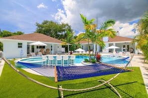A pool area with a hammock, lounge chairs, and a covered seating area. - Luxury Estate w/ Amazing Outdoor Space, Slps 24 (Bradenton)