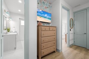 Un baño moderno con un lavamanos blanco, espejo y cómoda de madera con cajones.
