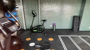 Une salle de sport équipée de matériel d’exercice, d’un vélo d’appartement et d’un mur décoré de motifs.