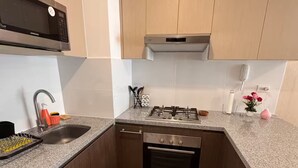 Une cuisine compacte équipée d’un four à micro-ondes, d’un évier, d’une cuisinière, d’un four et d’armoires en bois.