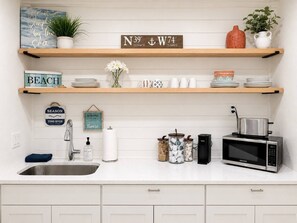 Una cucina con lavandino, forno a microonde e diversi utensili.