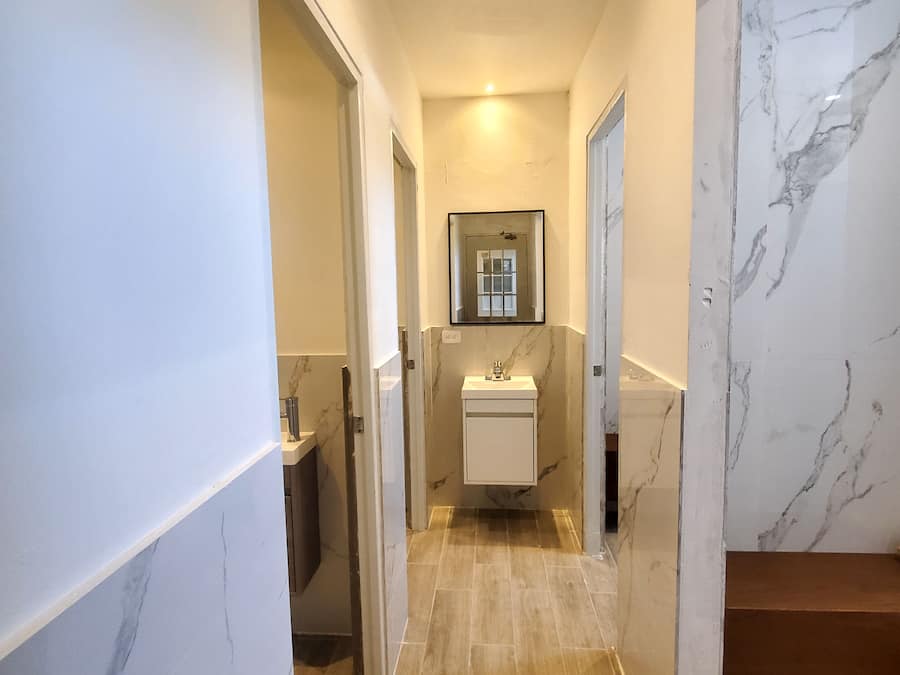 Un pasillo con paredes de mármol, un lavabo y un banco de madera.
