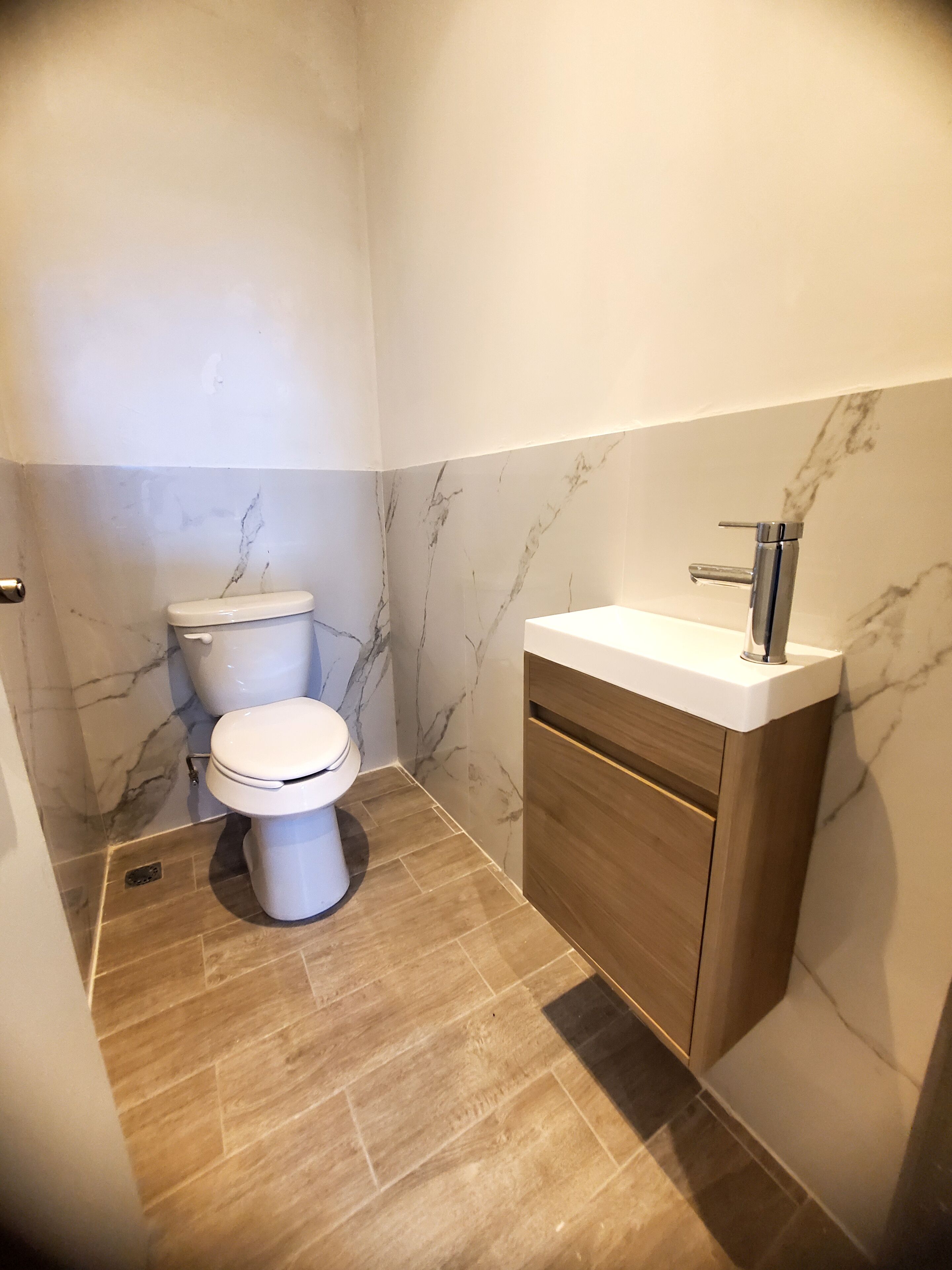 A bathroom with a toilet, a sink, and marble walls.