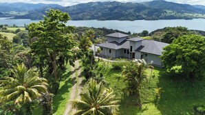 A house surrounded by lush greenery and a lake. - Panoramic Lake Arenal Sunset View Villa with AC (Nuevo Arenal)