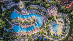 Een resort met meerdere zwembaden, ligbedden en palmbomen.