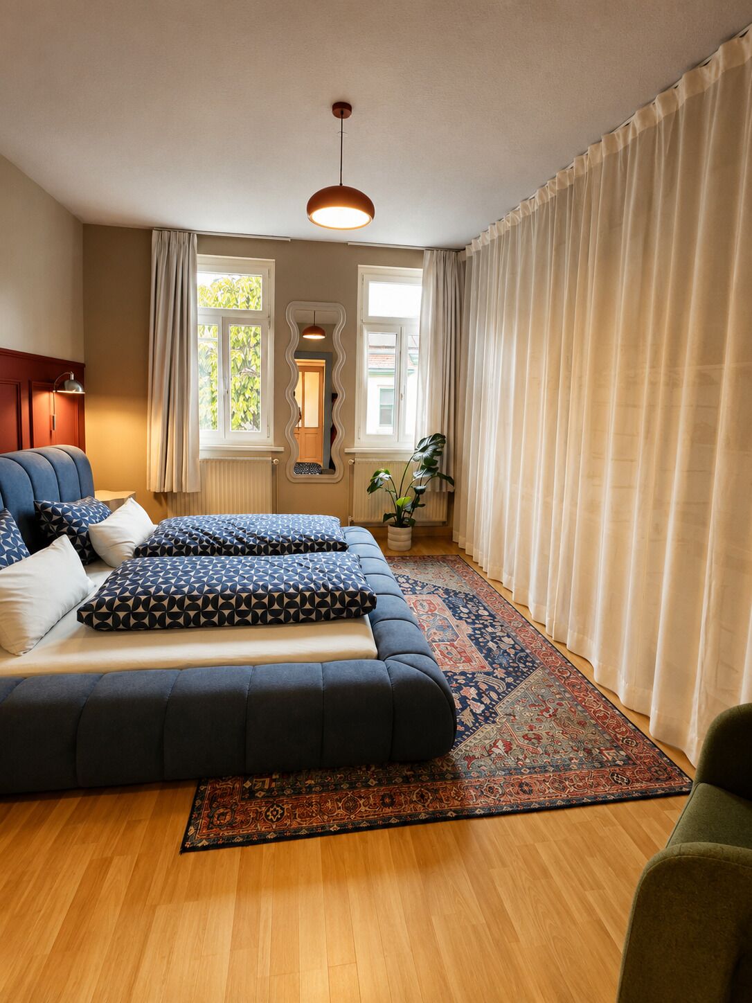 Un dormitorio moderno con una cama grande, un espejo, una lámpara colgante y vistas al exterior.