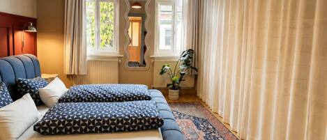 Un dormitorio moderno con una cama grande, un espejo, una lámpara colgante y vistas al exterior.