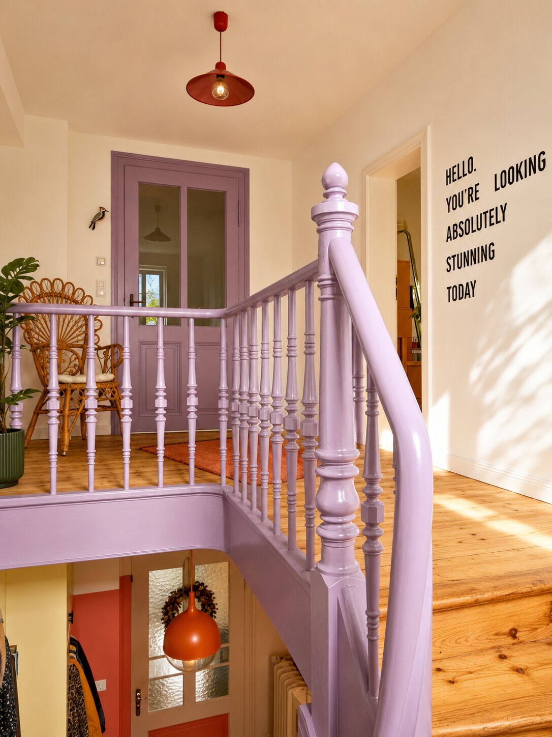 Eine Treppe mit einer violetten Geländer führt zu einer Zwischenebene mit einer Tür.