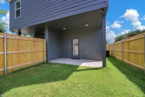 Ein Haus mit überdachter Terrasse, Holzzaun und gepflegtem Rasen.