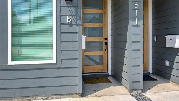 Una casa de fachada gris, puerta de madera y buzón.