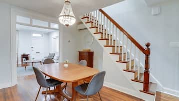 A dining area with a wooden table and chairs, a chandelier, and a staircase with wooden railings.