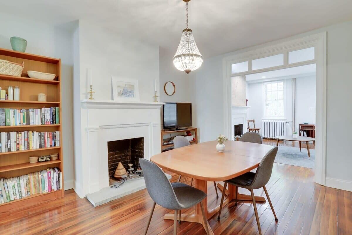 A dining area with a fireplace, bookshelves, and a chandelier.