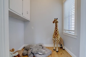 A room with a giraffe toy, a grey elephant toy, and a white cabinet.