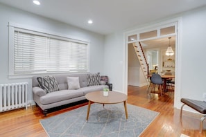 A living room with a sofa, a coffee table, and a dining area with chairs and a table.