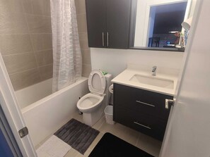 A bathroom with a bathtub, toilet, sink, and a mirror. - Modern Apartment You Can Enjoy in Heart of Markham 20 mins to Toronto or Airport (Markham)