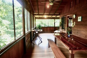 Un interior de madera con una mesa de comedor, bancos y ventanas amplias.