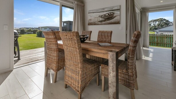 A dining area with wicker chairs, a wooden table, and a painting on the wall. - Waterfront Base with Private Pontoon and Kayaks (One Tree Point)