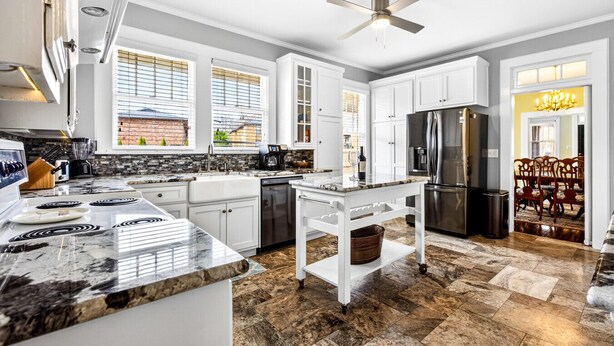 A modern kitchen with white cabinets, a granite countertop, a built-in oven, and a stainless steel refrigerator. - Historic Midtown Brick Home with Fire Pit (Columbus)