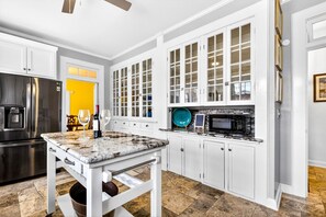 Eine moderne Küche mit weißen Schränken, einer Granit-Arbeitsplatte, einem Edelstahl-Kühlschrank und einer Mikrowelle.