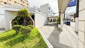 Un pati amb paviment de rajoles, un arbre petit i un edifici amb façana enrajolada.
