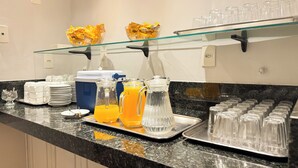 A breakfast buffet setup with various food items, beverages, and glassware.