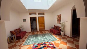 A spacious living area with a checkered floor, two sofas, a colorful rug, and a skylight.