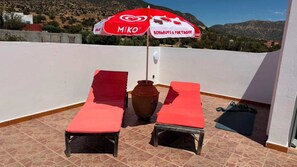 A rooftop terrace with two sun loungers, a large potted plant, and a red umbrella with 'MIKO' branding. - beautiful peaceful retreat with private garden and mountain views (owrir)