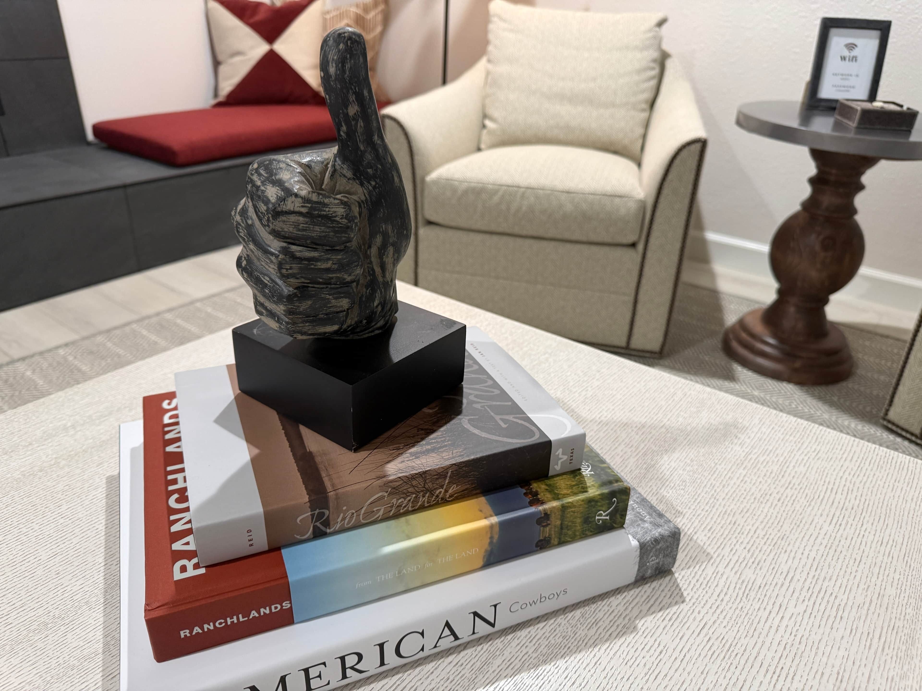 A sculpture on a black base, surrounded by books titled 'Ranchlands,' 'Rio Grande,' and 'American Cowboys.'