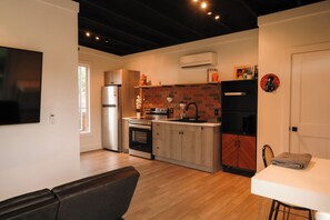 A modern kitchen with a brick backsplash, stainless steel appliances, and a dining area with a table and chairs. - Marion Cabin private pool, pickleball, park, walking paths, and put-put golf (Marion)