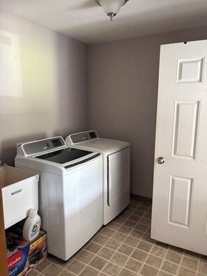 A laundry room with a front-loading washer and dryer, a door, and a box of laundry detergent.