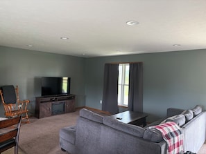 A living room with a sofa, TV, wooden chair, and a fireplace.
