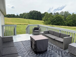 A covered outdoor deck with wicker furniture, including a sofa and chairs, and a table with a tablecloth.