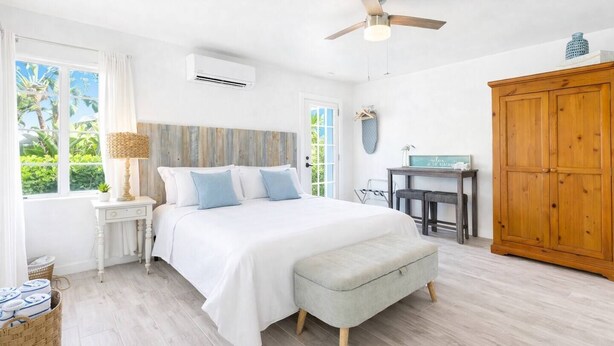 A bedroom with a bed, a desk, a wardrobe, and a ceiling fan. - Lido Bungalow Walk to Beach & St. Armand's Circle (Sarasota)