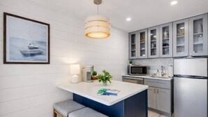 Cozinha moderna com ilha central, eletrodomésticos de aço inoxidável e luminária pendente.