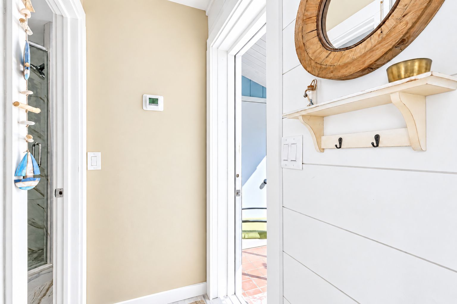 Una habitación con una pared color beige, una puerta blanca y un espejo con marco de madera.