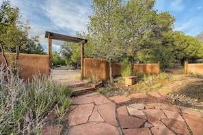 A garden with a pergola, stone pathway, and various plants.