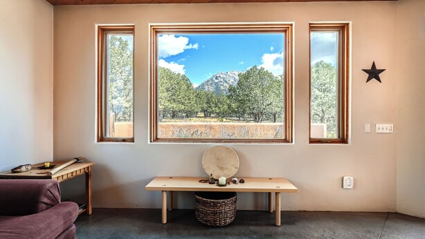 A room with a large window, a wooden bench, a star decoration, and a wicker basket.