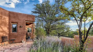 A rustic building with a stone patio, outdoor seating, and a garden with various plants.